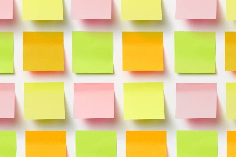 Grid of colorful sticky notes creating a vibrant pattern on a white surface.